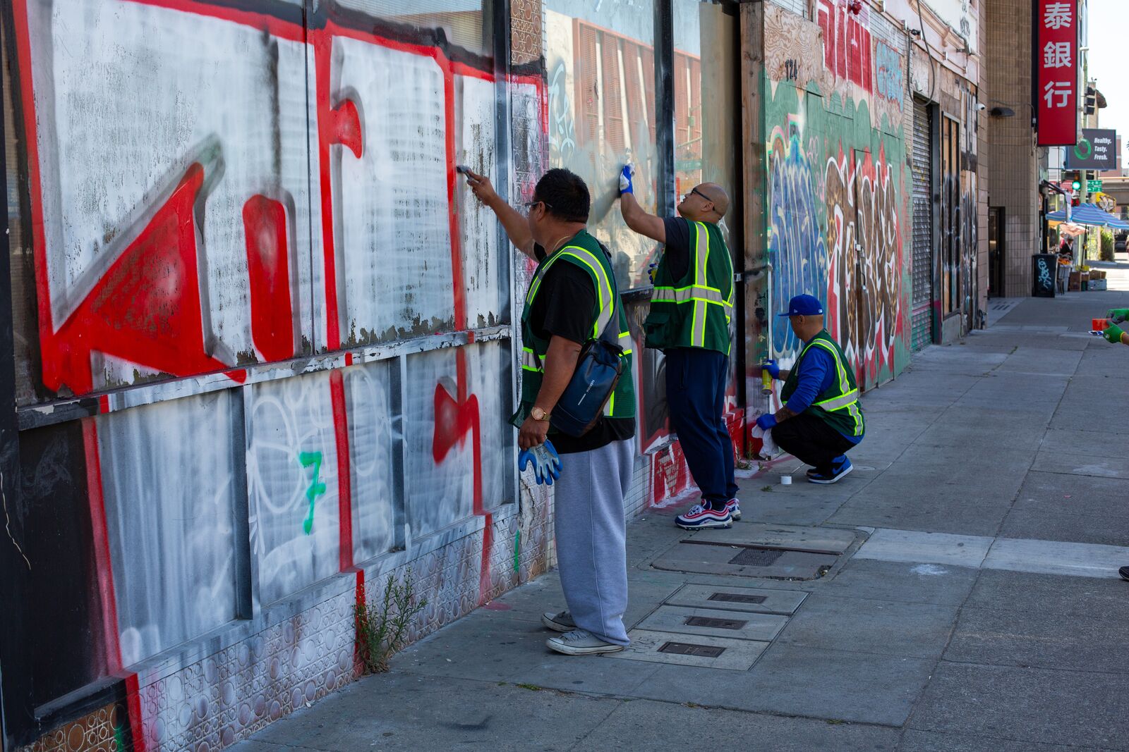 Volunteers with Asian Pacific American Advocates clean graffiti from a window in Oakland Chinatown on June 9, 2024. Credit: Amaya Edwards