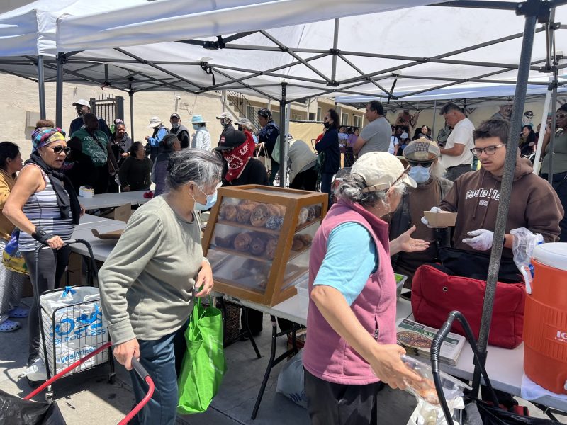 Groups of people gathering to receive food at the Sliding Scale Cafe.