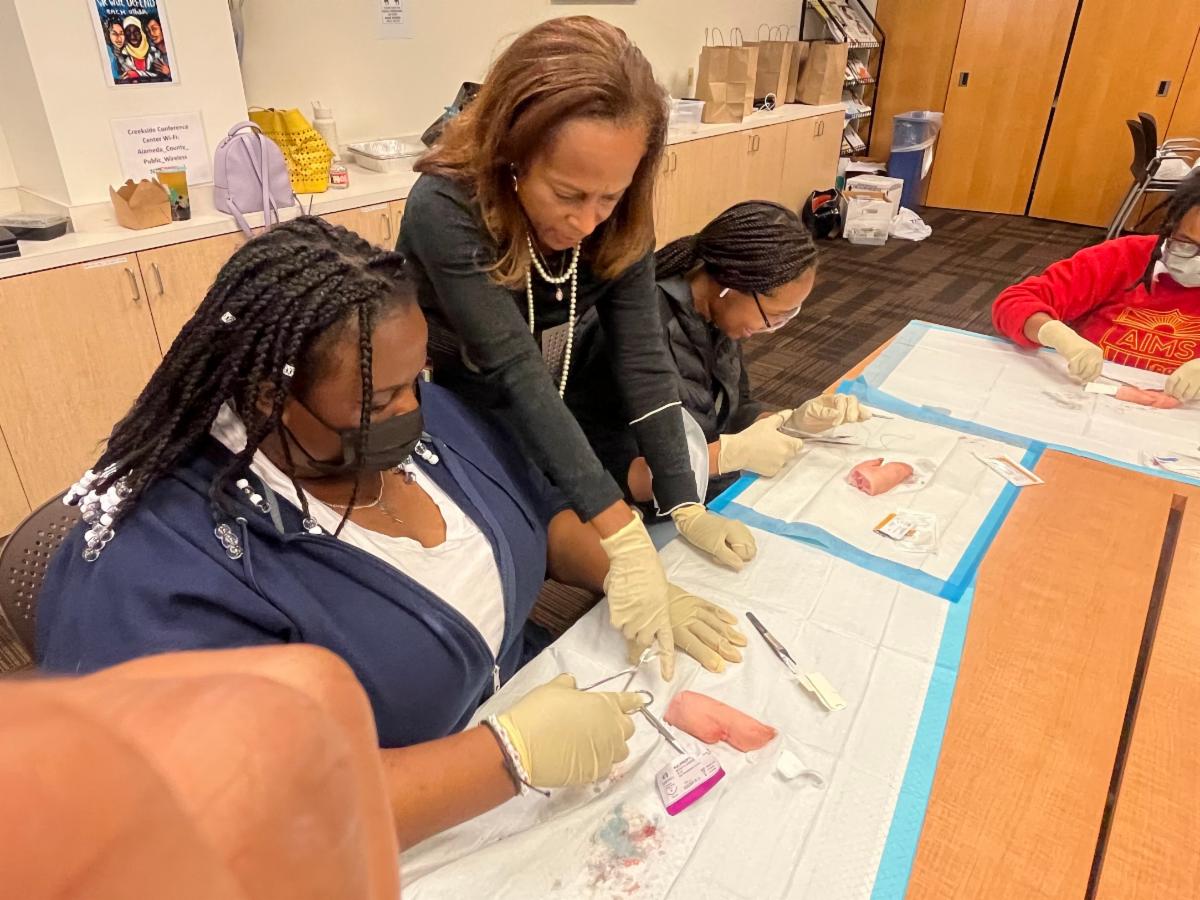 woman shows a younger woman suturing